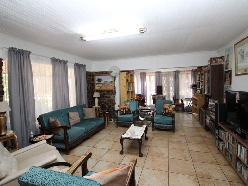 Spacious living room featuring rustic stone wall accents, tiled flooring, and large windows allowing for ample natural light.