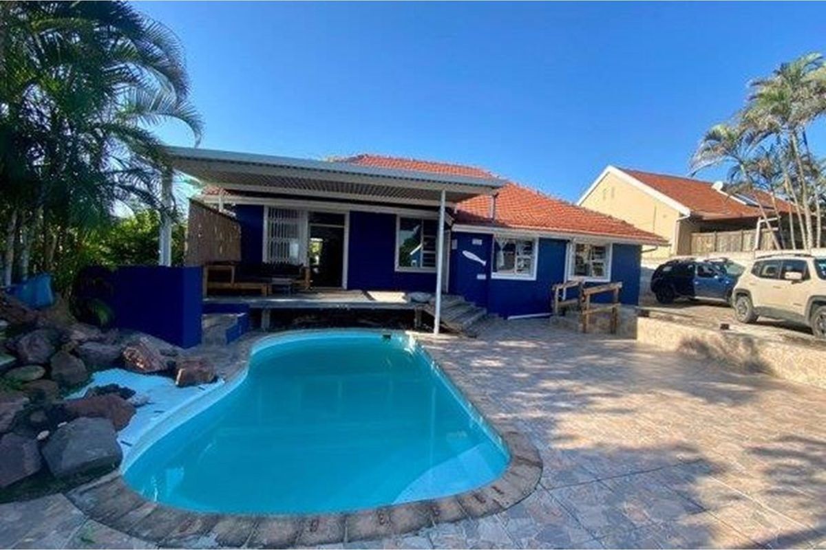 Rear exterior view featuring a swimming pool, covered patio area, and tiled outdoor space with blue painted exterior walls.