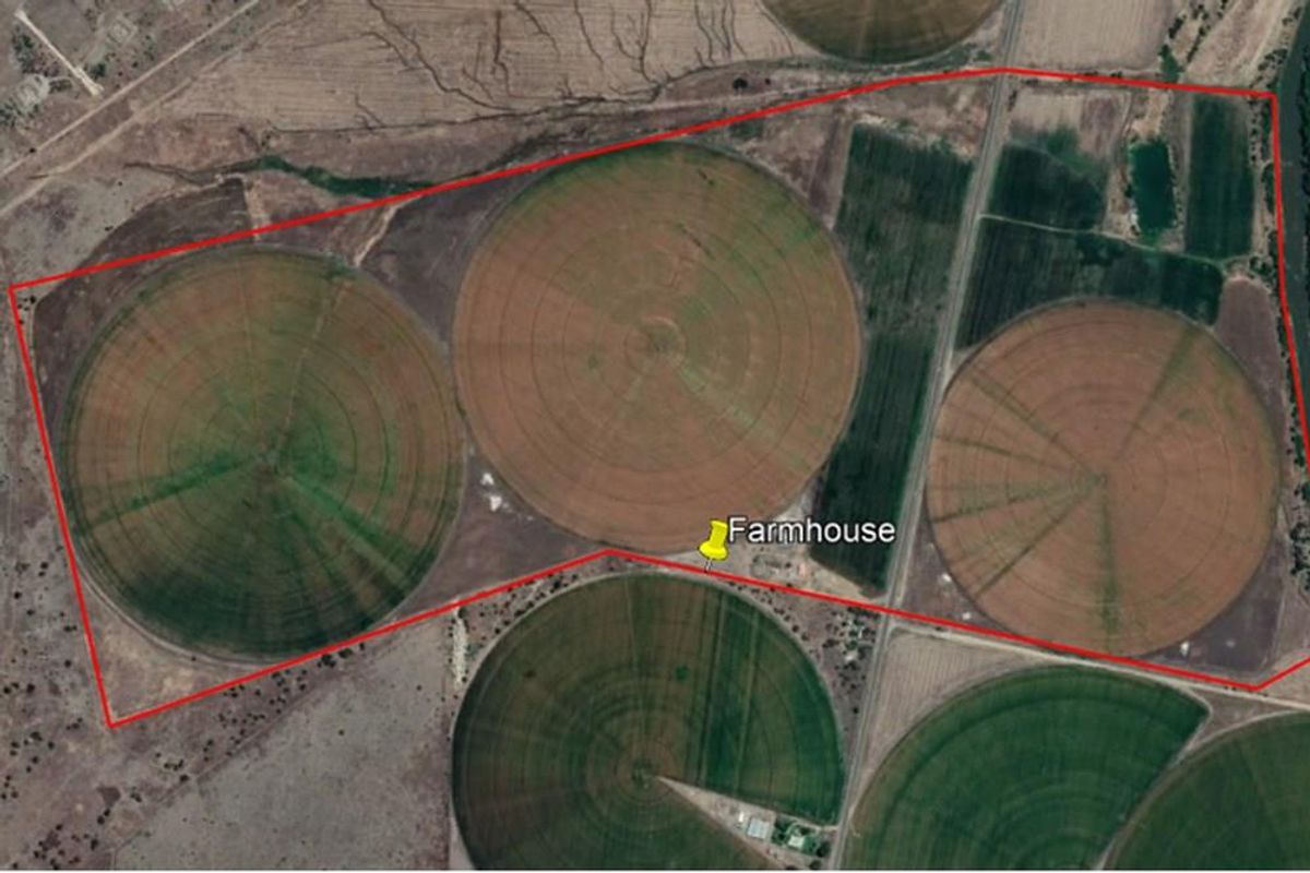 Aerial view of a large-scale farm property featuring multiple circular irrigation fields and a designated farmhouse location.