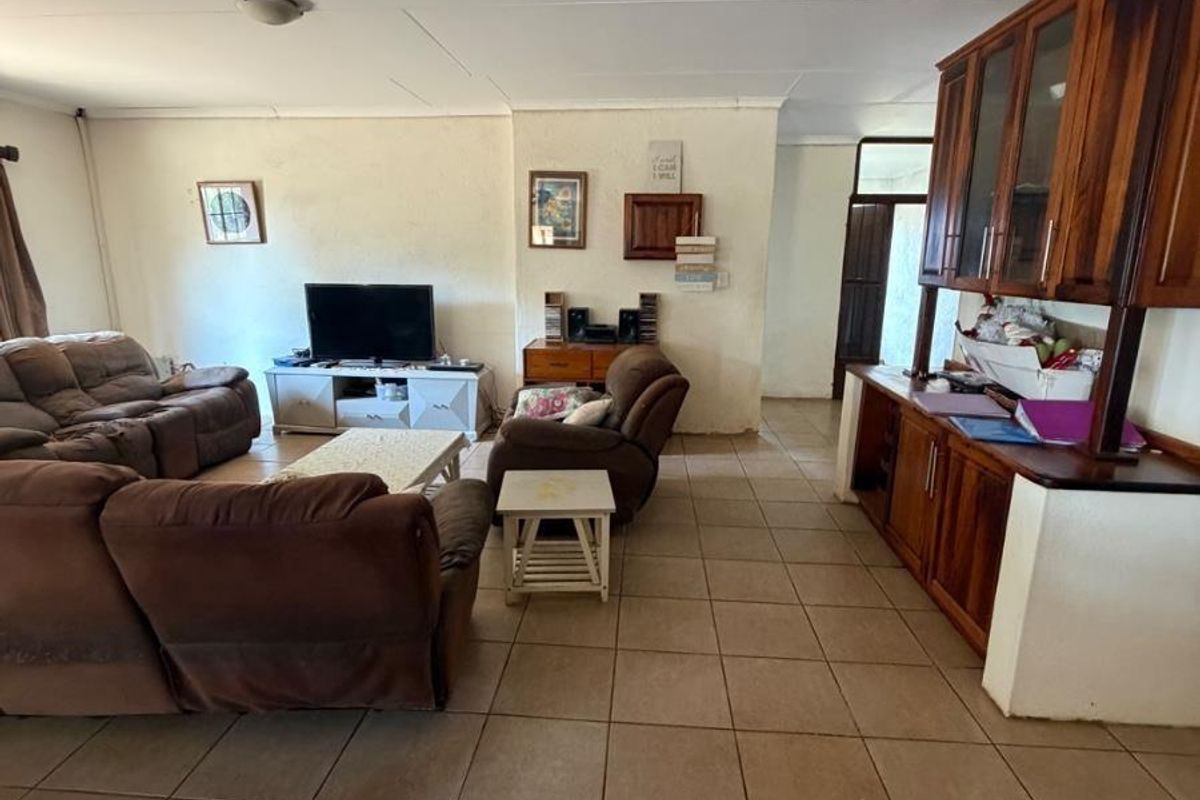 Spacious living area featuring tiled flooring and integrated wooden cabinetry, offering a functional layout with potential for modern updates.
