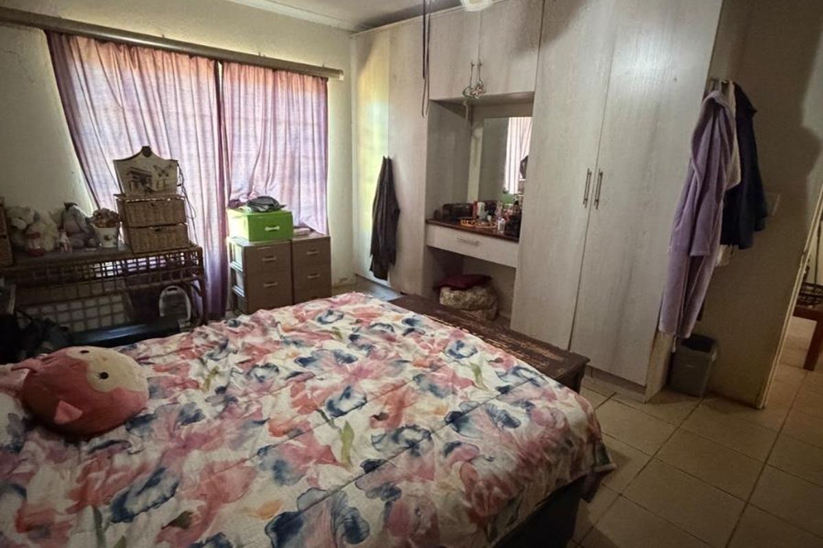 Bedroom featuring built-in cupboards with an integrated vanity, tiled flooring, and a ceiling fan. The room requires cosmetic updates to the ceiling and walls.