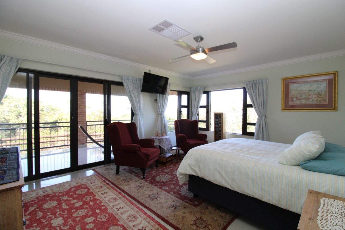 Spacious bedroom featuring large sliding glass doors leading to a private balcony, ceiling fan, and neutral wall finishes.