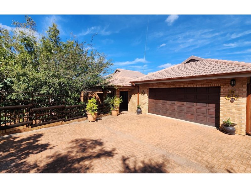 Front exterior view of the house featuring a brick facade, tiled roof, paved driveway, and a double garage.