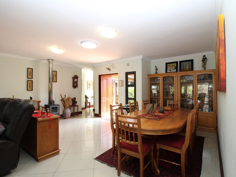 Spacious open-plan living and dining area featuring polished tile flooring, a built-in wood-burning fireplace, and direct access to the entrance.