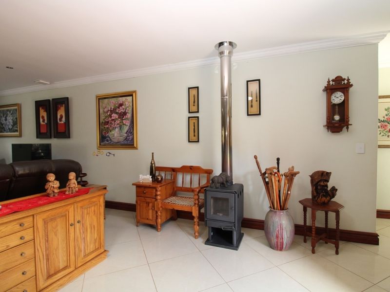 A spacious living area featuring light-colored floor tiles, crown molding, and a modern freestanding metal fireplace with a stainless steel flue.