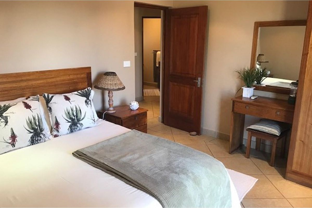 A bedroom featuring tiled flooring and a wooden door leading to an adjoining bathroom.