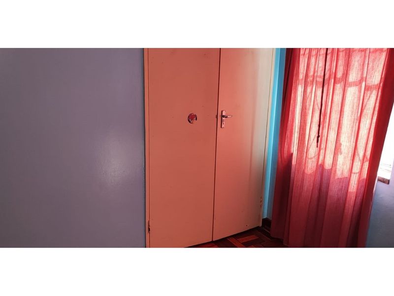 A bedroom featuring parquet flooring and a built-in wardrobe, providing essential storage space.