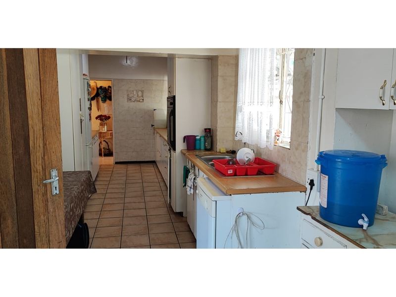 A functional kitchen featuring tiled flooring, built-in cabinetry, and a tiled backsplash, offering a practical layout with potential for modern updates.