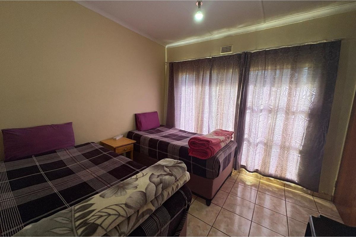 A bedroom featuring tiled flooring and large sliding glass doors with curtains, providing natural light and access to the exterior.