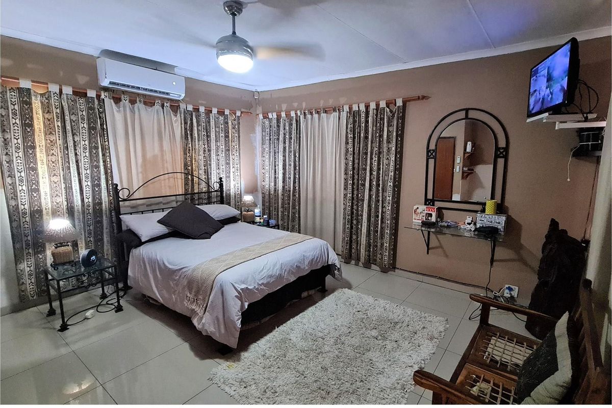 A bedroom featuring tiled flooring, a ceiling fan, and a wall-mounted air conditioning unit.