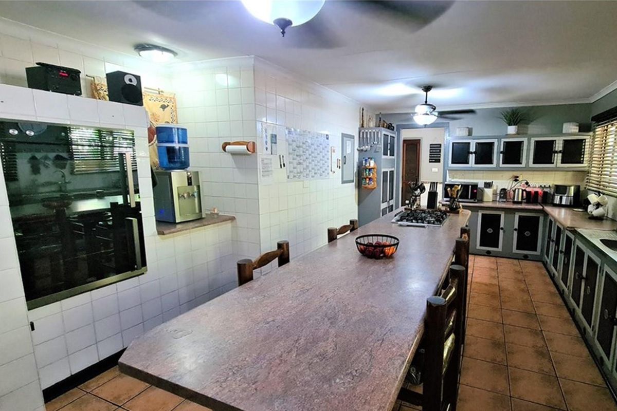 Spacious kitchen featuring a long central island, built-in cabinetry, tiled walls, and integrated cooking hob.