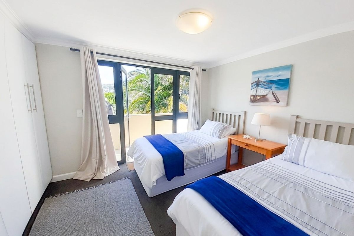 A well-maintained bedroom featuring built-in cupboards, carpeted flooring, and a sliding glass door providing access to an outdoor balcony area.
