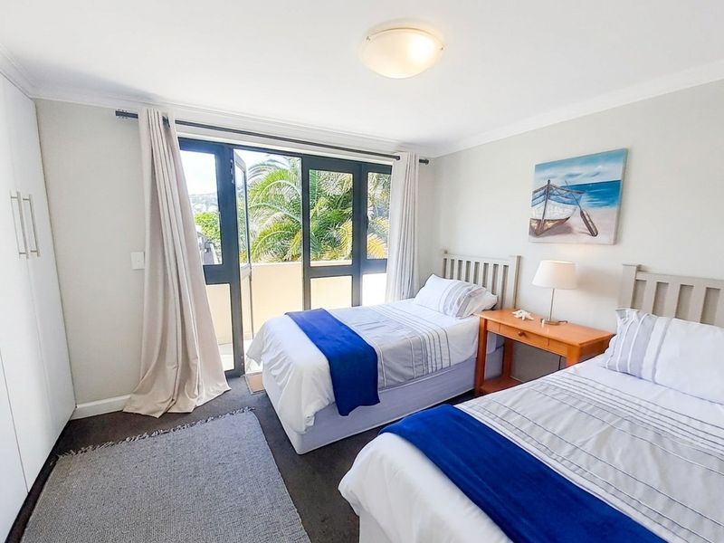 A well-maintained bedroom featuring built-in cupboards, carpeted flooring, and a sliding glass door providing access to an outdoor balcony area.