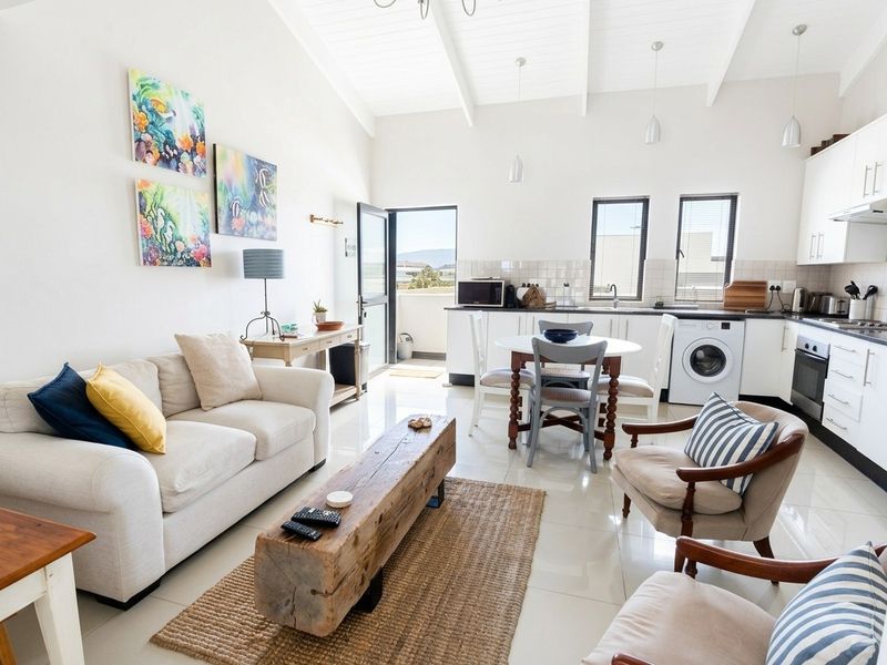 Bright open-plan living area featuring a modern kitchen with built-in appliances, vaulted ceilings, and direct access to a private balcony.