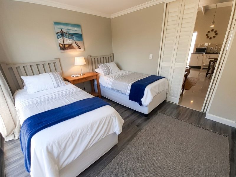 A well-maintained bedroom featuring laminate flooring, crown molding, and bi-fold doors leading to an adjacent living area.