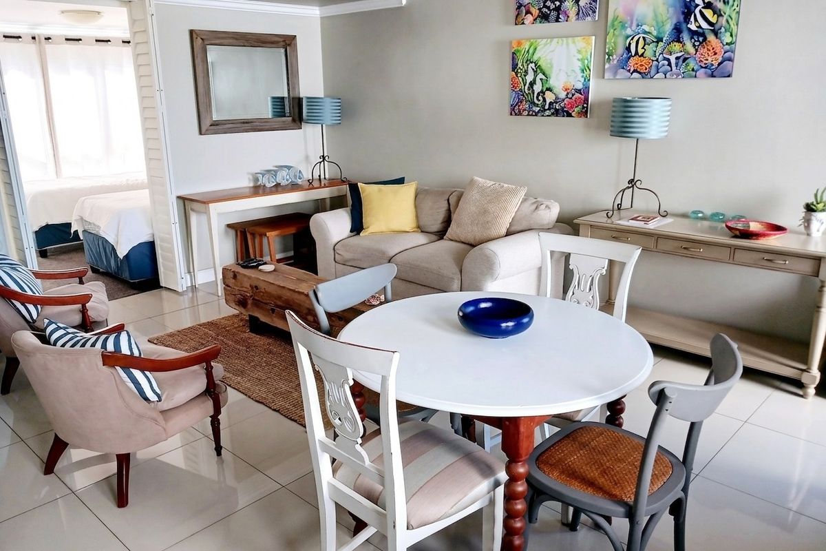 A bright living area featuring tiled flooring and an open layout with a view into the adjacent bedroom.