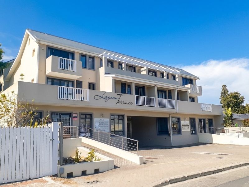 Front elevation of Lagoon Terrace apartment complex featuring multi-level balconies, paved driveway, and ramp access.