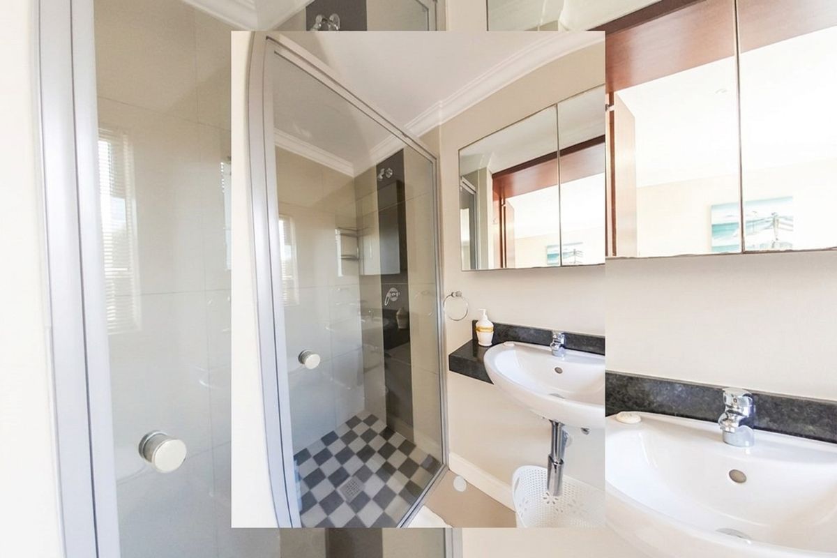 A compact bathroom featuring a glass-enclosed shower, vanity basin with stone countertop, and a mirrored medicine cabinet.
