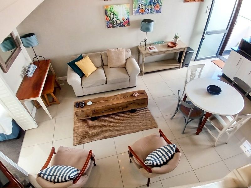 An open-plan living and dining area featuring tiled flooring, neutral wall tones, and direct access to an outdoor space via a glass sliding door.