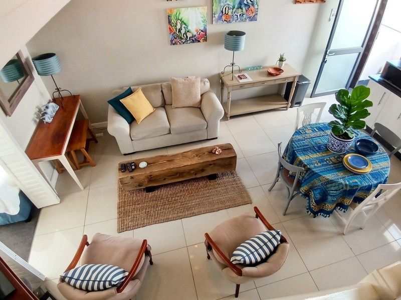 An elevated view of an open-plan living and dining area featuring tiled floors and direct access to an outdoor space.