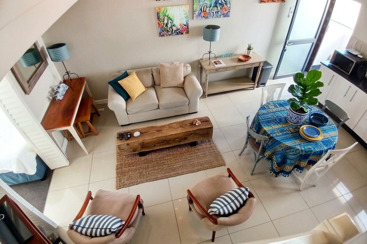 An elevated view of an open-plan living and dining area featuring tiled floors and direct access to an outdoor space.