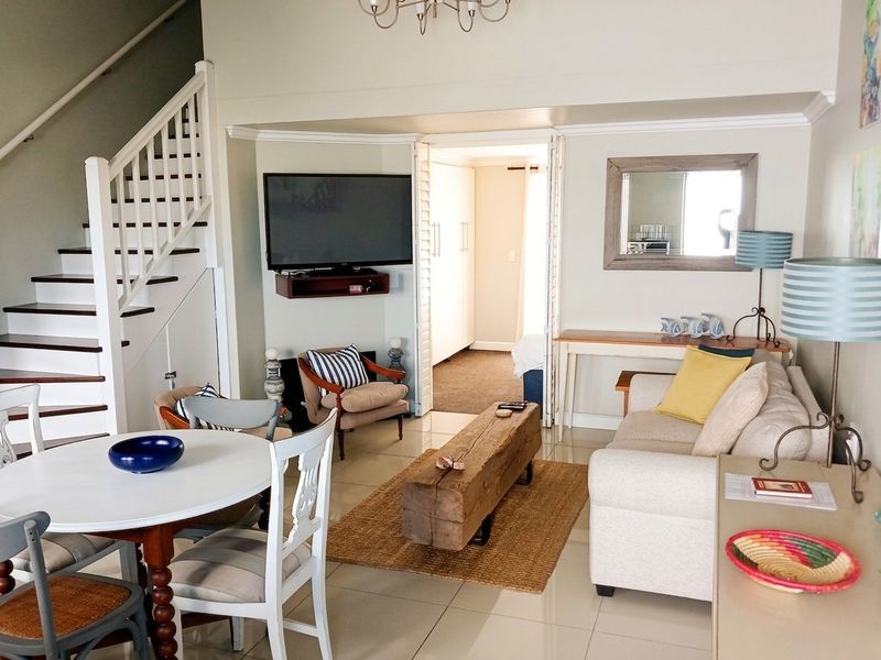 Open-plan living and dining area featuring a staircase, tiled flooring, and bi-fold doors leading to an adjacent room.