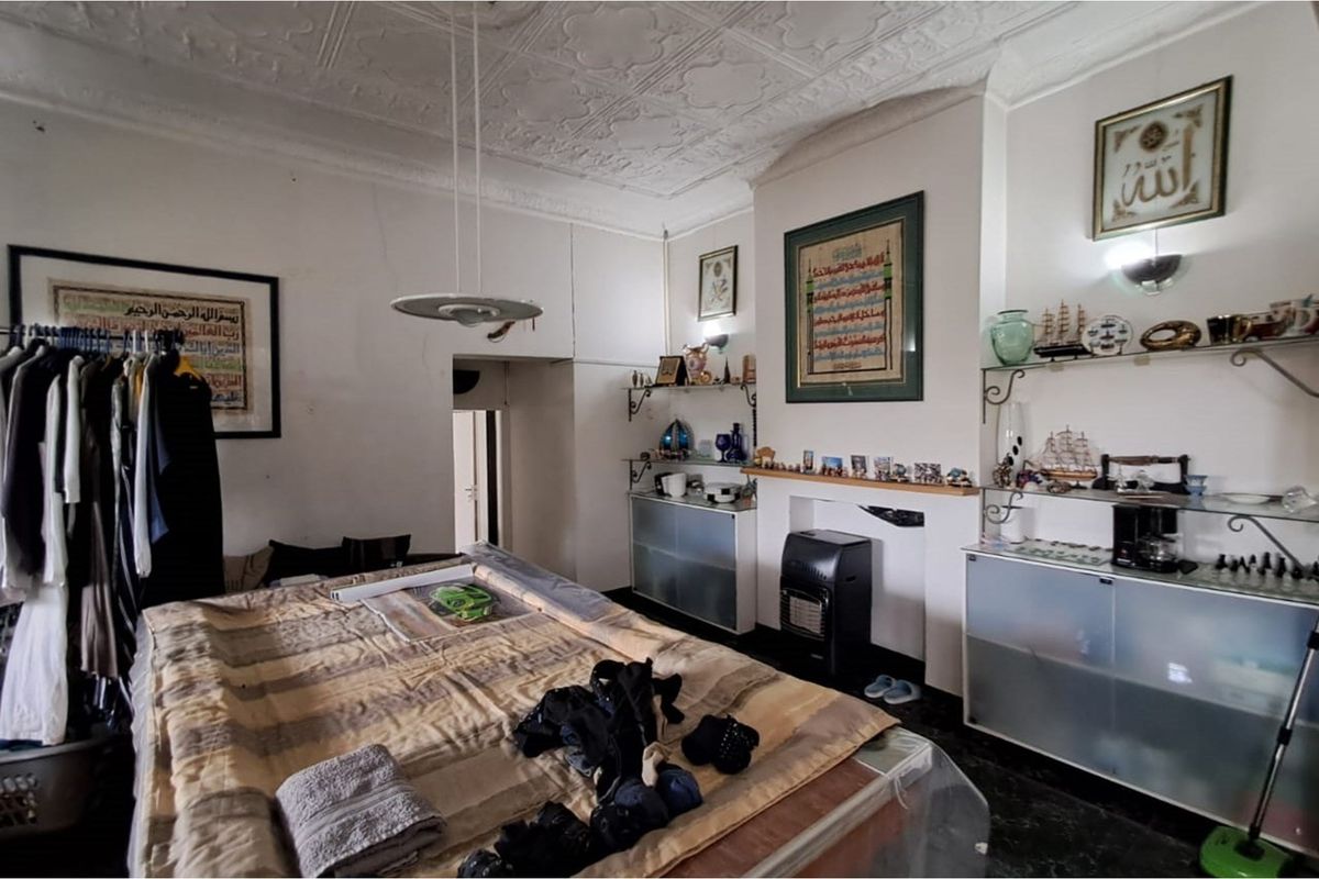 A bedroom featuring a decorative pressed tin ceiling, a fireplace alcove with built-in shelving, and dark flooring.