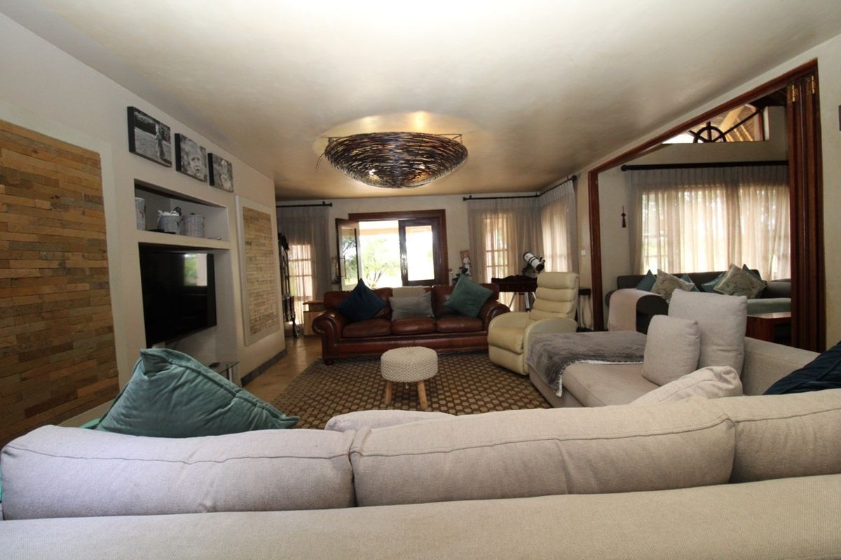 Spacious living room featuring timber wall accents, built-in shelving, and bi-fold doors leading to an outdoor area, creating a warm and inviting atmosphere.