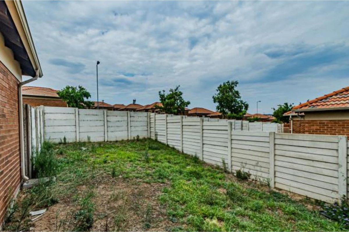 A private rear garden area featuring a precast concrete boundary wall and an unmaintained lawn space.