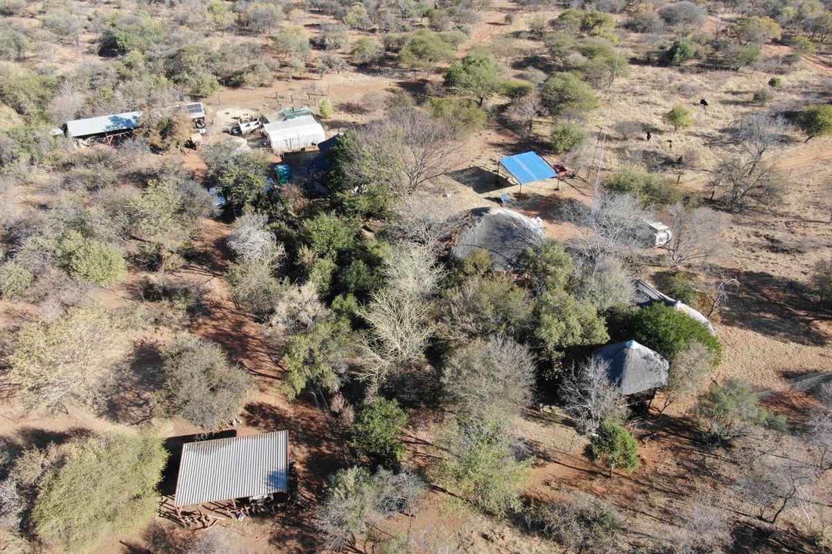 Aerial view of a rural farm property featuring multiple outbuildings, thatched roof structures, and extensive natural bushveld landscape.