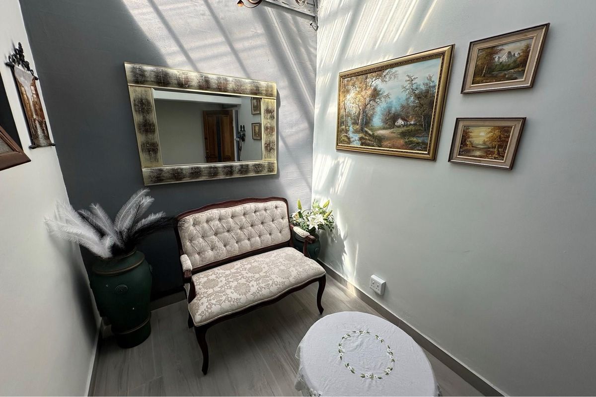 A bright, intimate seating area featuring a skylight, neutral wall finishes, and light-toned flooring, creating a welcoming and well-lit space.