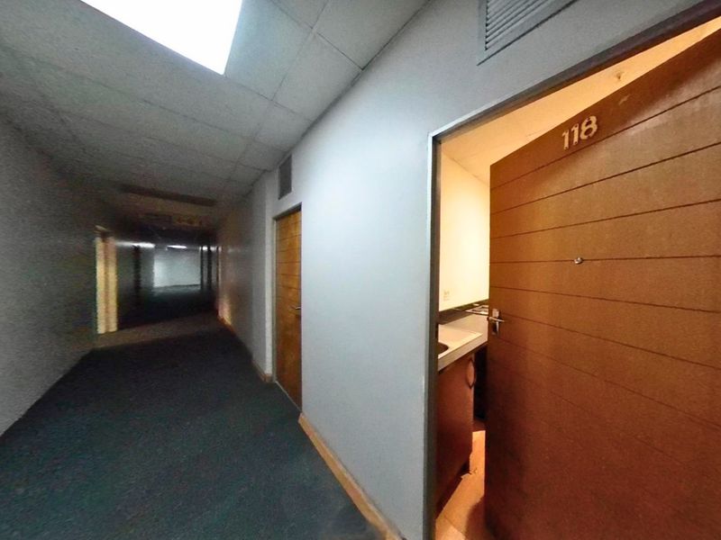 A view of a commercial-style apartment building hallway with drop ceilings, carpeted flooring, and access to unit 118.