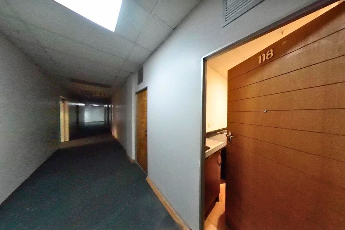 A view of a commercial-style apartment building hallway with drop ceilings, carpeted flooring, and access to unit 118.