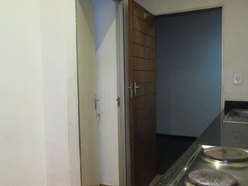A compact kitchen area featuring a built-in electric hob, granite countertops, and a stainless steel sink, with direct access to an adjacent room.