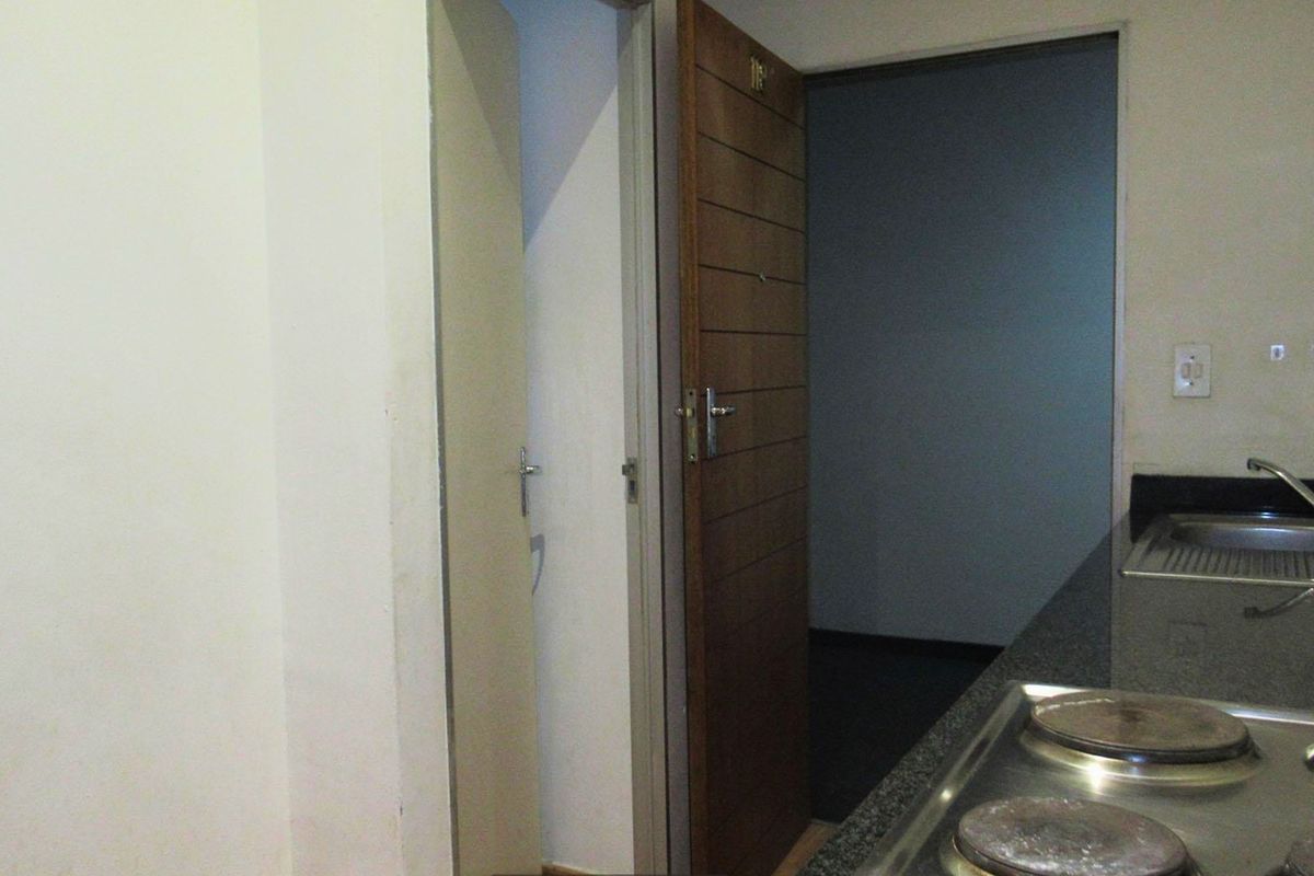 A compact kitchen area featuring a built-in electric hob, granite countertops, and a stainless steel sink, with direct access to an adjacent room.