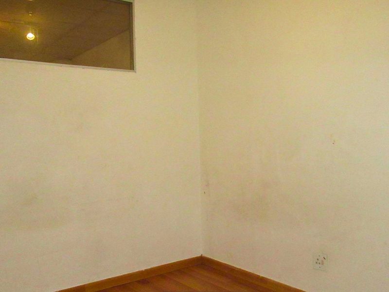 An empty bedroom featuring laminate flooring and a high-level window, requiring cosmetic attention to the wall surfaces.