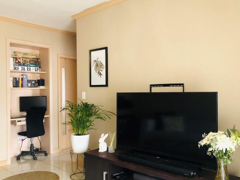 A living room area featuring a built-in study nook with shelving and tiled flooring.