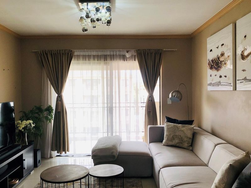 A comfortable living room featuring tiled flooring, crown molding, and a sliding glass door that provides access to an outdoor balcony area.