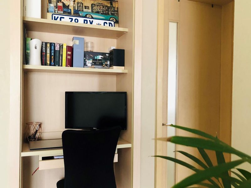 A built-in wooden study nook featuring integrated shelving and a dedicated desk space, providing a functional work area within the apartment.