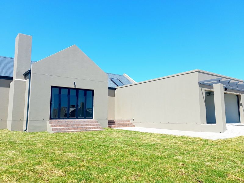Rear view of a modern house featuring a chimney, solar panels, tiled steps, and an attached garage with a pergola.