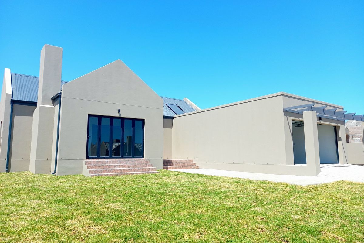 Rear view of a modern house featuring a chimney, solar panels, tiled steps, and an attached garage with a pergola.