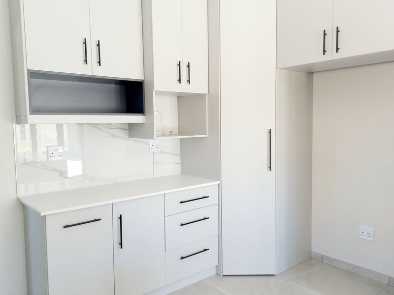 Modern kitchen featuring sleek white cabinetry, marble-look splashback, stone countertops, and ample storage space, presented in a clean, minimalist style.