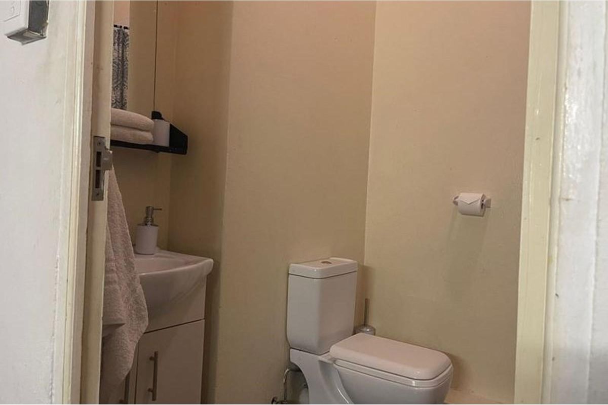 A compact bathroom featuring a white toilet and a small vanity basin with integrated storage.