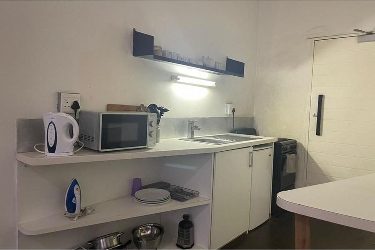 A compact kitchen area featuring basic cabinetry, a stainless steel sink, and a freestanding stove, providing essential functionality in a modest apartment setting.