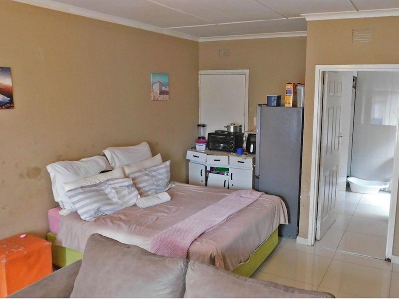 Open plan living and sleeping area featuring tiled flooring and direct access to an adjoining room.