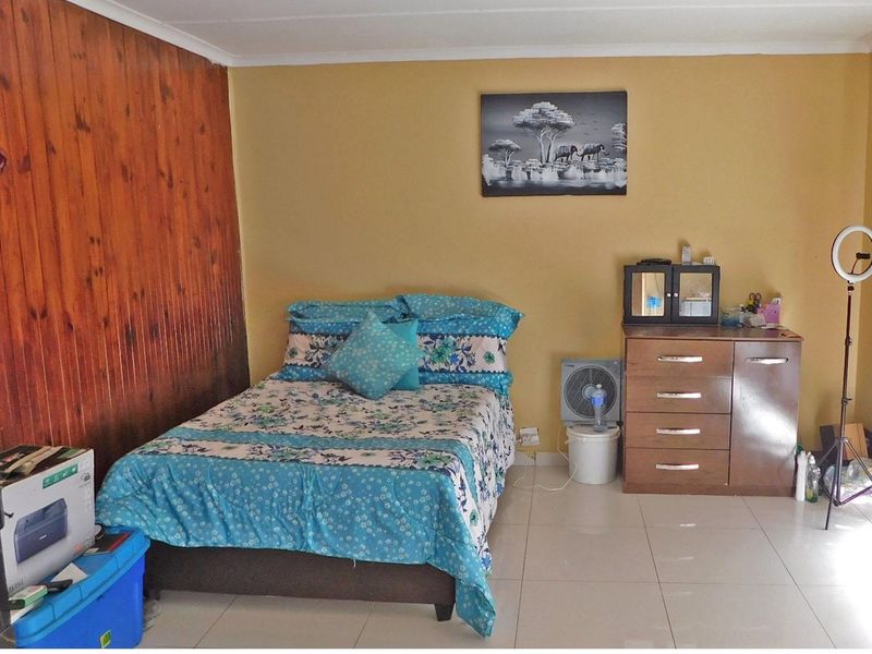 A bedroom featuring tiled flooring and a wood-paneled accent wall, providing a functional space with neutral wall tones.