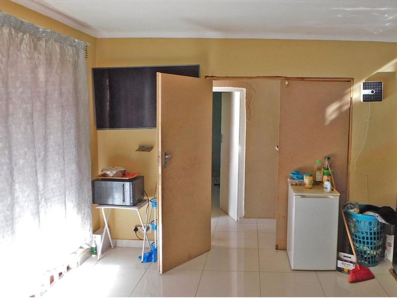 Living area featuring tiled flooring and an internal doorway with visible plaster damage and unfinished door frame surrounds.