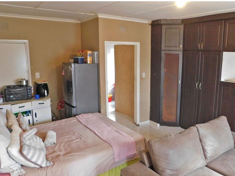A bedroom featuring built-in dark wood cupboards and tiled flooring, offering a functional layout with direct access to an adjacent room.