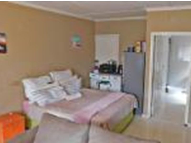 A bedroom featuring neutral wall tones and coving, providing a functional sleeping space with direct access to an adjoining room.