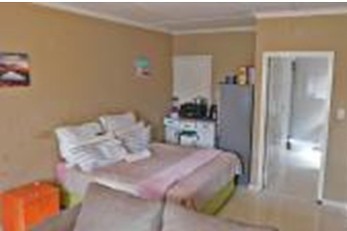 A bedroom featuring neutral wall tones and coving, providing a functional sleeping space with direct access to an adjoining room.